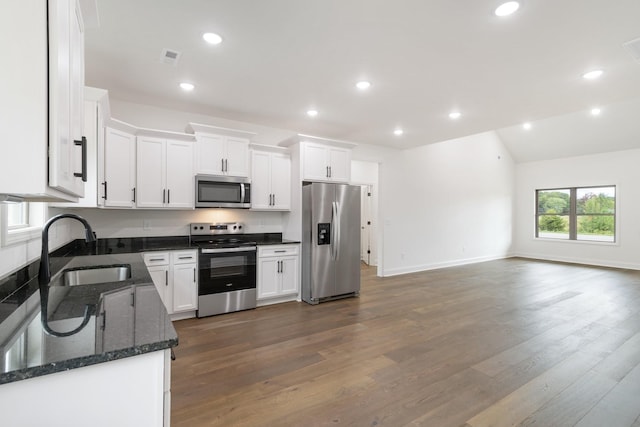 kitchen with sink, dark wood-type flooring, white cabinetry, stainless steel appliances, and dark stone counters