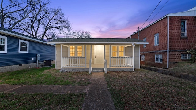 view of front of property with a lawn, central air condition unit, and covered porch