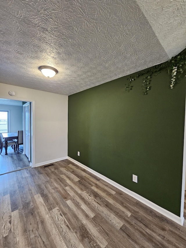 empty room with hardwood / wood-style flooring and a textured ceiling