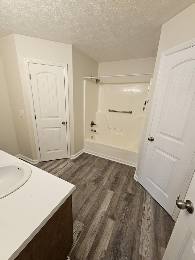 bathroom with hardwood / wood-style floors, a textured ceiling, vanity, and tub / shower combination