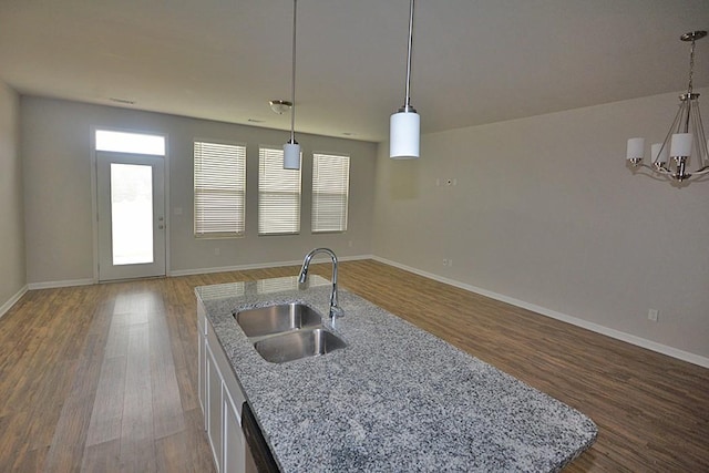 kitchen with pendant lighting, sink, light stone counters, and wood-type flooring