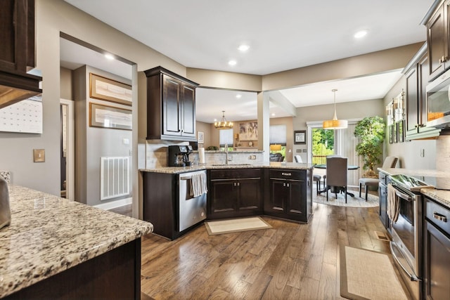 kitchen featuring sink, dark brown cabinets, hanging light fixtures, appliances with stainless steel finishes, and hardwood / wood-style flooring