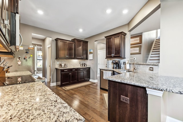 kitchen featuring dark brown cabinetry, tasteful backsplash, dark wood finished floors, light stone counters, and a sink