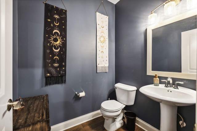 bathroom with wood finished floors, toilet, and baseboards