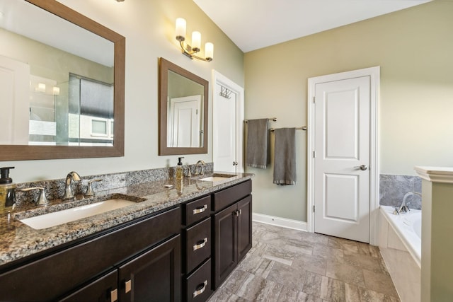 bathroom with a bath, double vanity, baseboards, and a sink