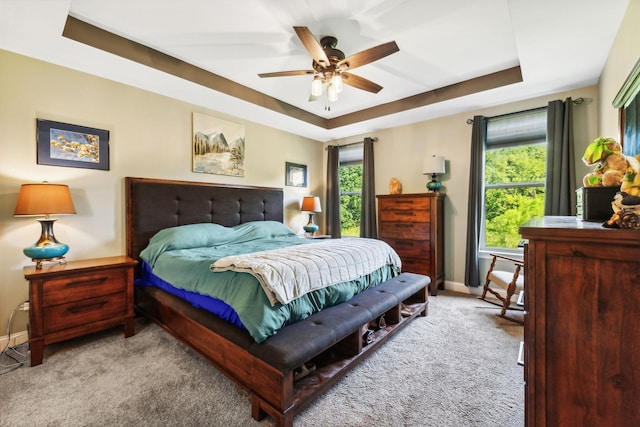 carpeted bedroom featuring ceiling fan and a tray ceiling