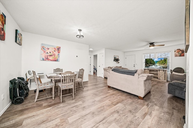 living room with ceiling fan, a textured ceiling, and light hardwood / wood-style flooring