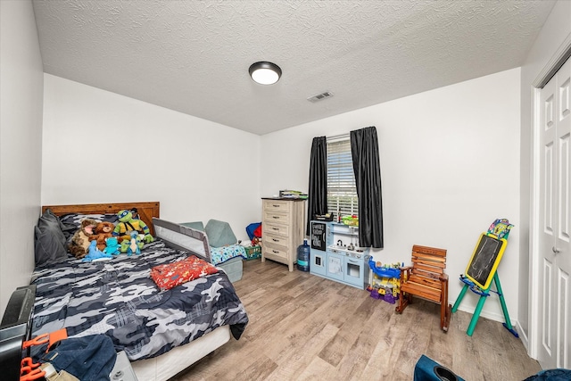 bedroom with light hardwood / wood-style flooring and a textured ceiling