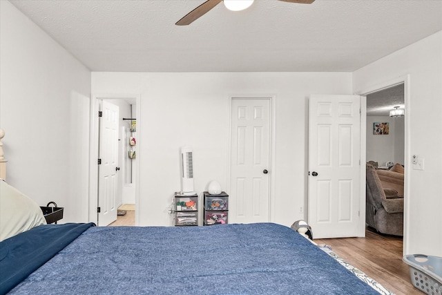 bedroom featuring ceiling fan, connected bathroom, a textured ceiling, and light hardwood / wood-style flooring