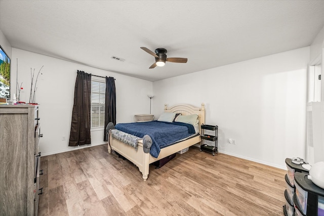 bedroom with ceiling fan, light hardwood / wood-style floors, and a textured ceiling