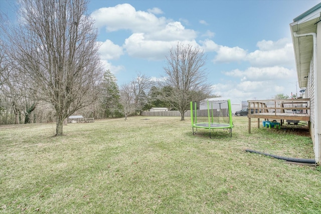 view of yard with a wooden deck and a trampoline