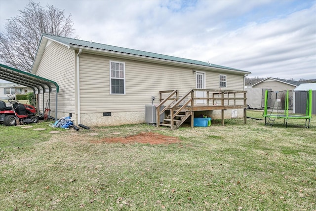 back of property featuring cooling unit, a deck, a trampoline, and a lawn