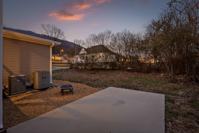 yard at dusk featuring central AC, a patio area, and an outdoor fire pit