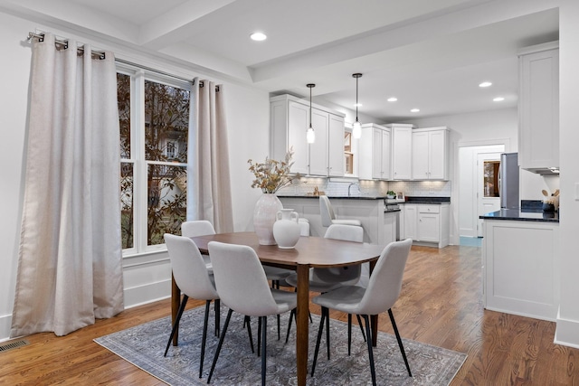 dining room with beamed ceiling, dark hardwood / wood-style floors, and sink