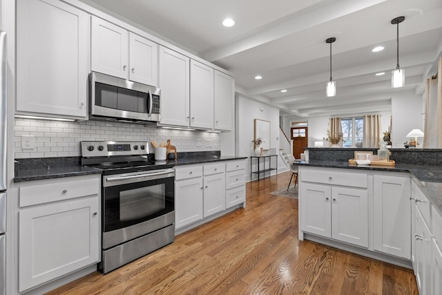 kitchen with appliances with stainless steel finishes, backsplash, light hardwood / wood-style floors, white cabinets, and decorative light fixtures