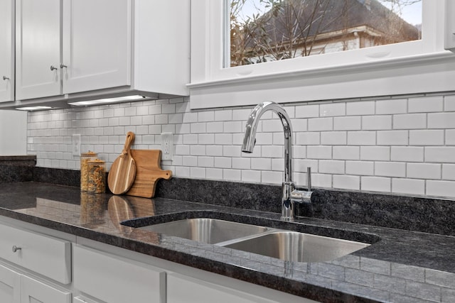 kitchen with sink, dark stone countertops, white cabinets, and decorative backsplash