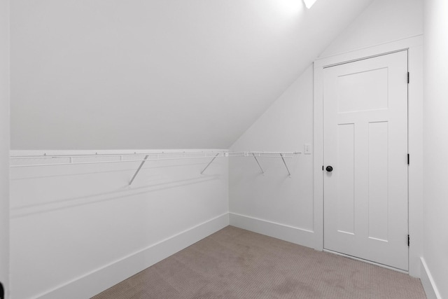 spacious closet with lofted ceiling and light carpet