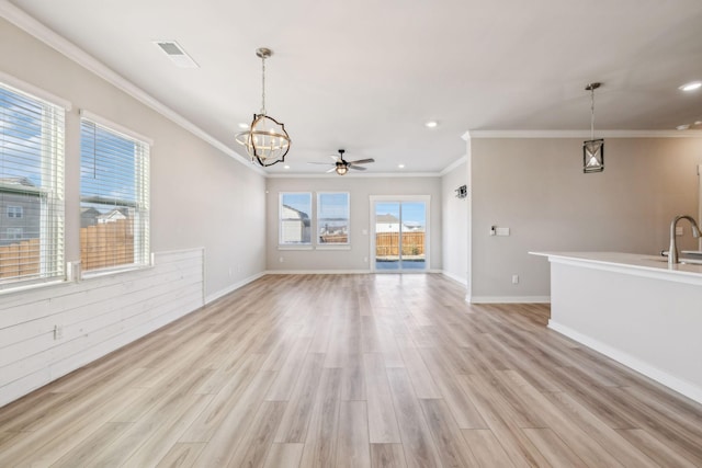 unfurnished living room with ornamental molding, sink, ceiling fan with notable chandelier, and light hardwood / wood-style flooring