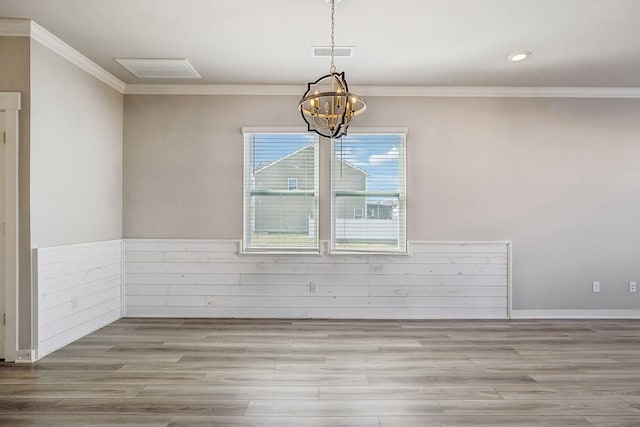 spare room featuring a notable chandelier, ornamental molding, and light wood-type flooring