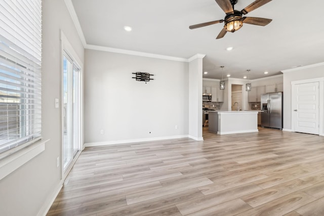 unfurnished living room with crown molding, ceiling fan, sink, and light hardwood / wood-style flooring