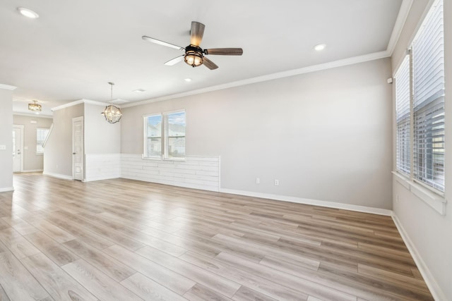 unfurnished living room with ornamental molding, ceiling fan with notable chandelier, and light wood-type flooring