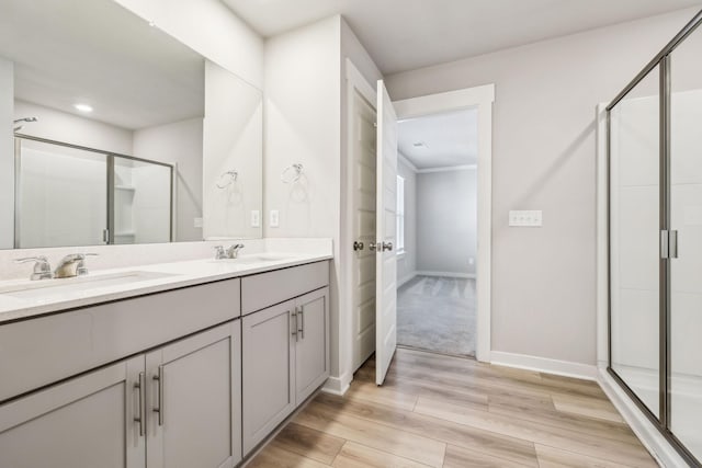 bathroom featuring an enclosed shower, vanity, and wood-type flooring