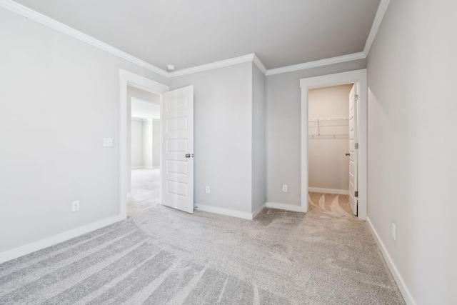 unfurnished bedroom featuring light carpet, a spacious closet, and ornamental molding