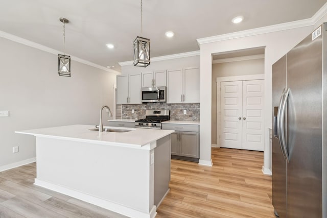 kitchen featuring a kitchen island with sink, sink, pendant lighting, and appliances with stainless steel finishes