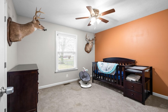 bedroom featuring light carpet, a crib, and ceiling fan