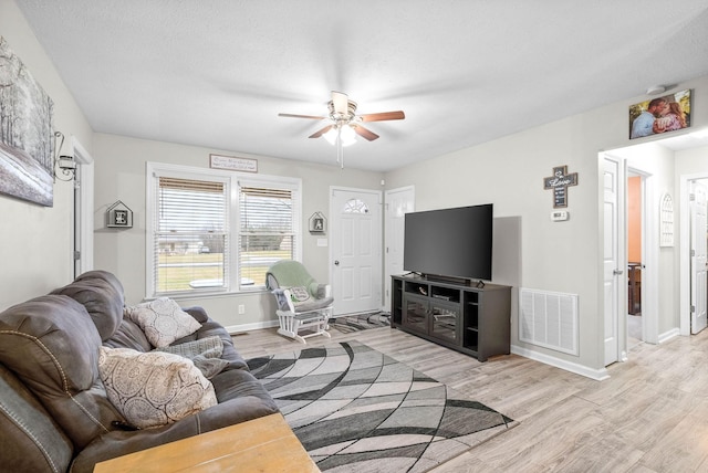 living room featuring ceiling fan, a textured ceiling, and light wood-type flooring