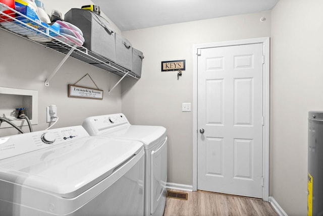 laundry area featuring washing machine and dryer and light wood-type flooring