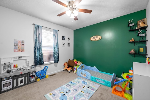 recreation room featuring ceiling fan, carpet, and a textured ceiling