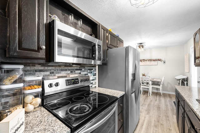 kitchen featuring stainless steel appliances, a textured ceiling, light stone counters, and decorative backsplash