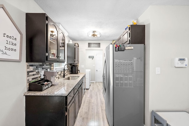 kitchen featuring sink, washer and clothes dryer, stainless steel fridge, backsplash, and light hardwood / wood-style floors