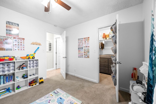 game room featuring light carpet, a textured ceiling, and ceiling fan