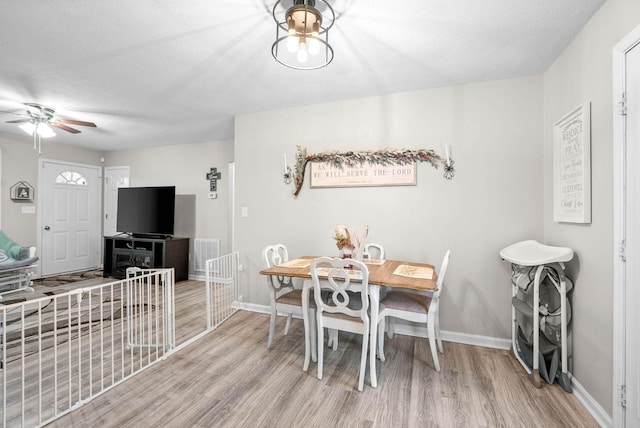 dining area with a textured ceiling, ceiling fan, and light wood-type flooring