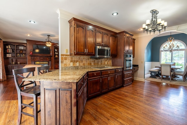 kitchen with crown molding, appliances with stainless steel finishes, a breakfast bar area, and decorative light fixtures