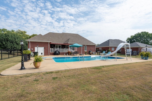 view of swimming pool with a patio, a water slide, a diving board, and a lawn