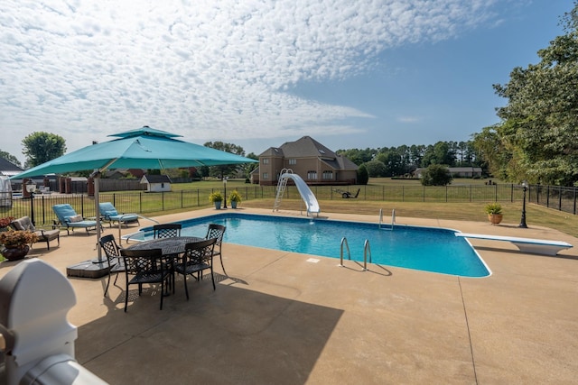 view of swimming pool with a water slide, a patio, and a lawn