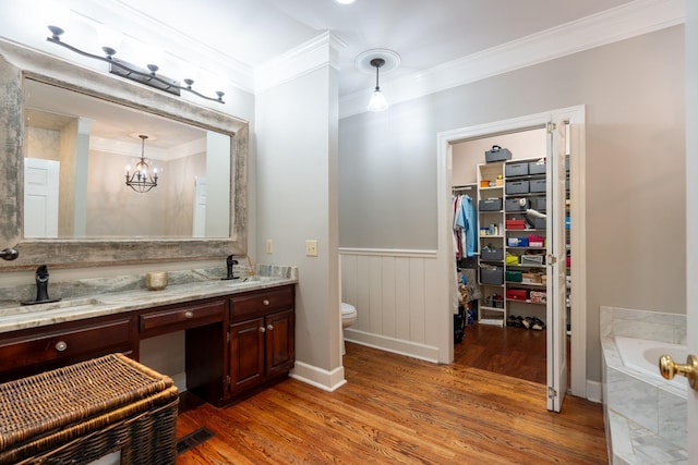 bathroom with tiled tub, crown molding, hardwood / wood-style flooring, vanity, and a chandelier