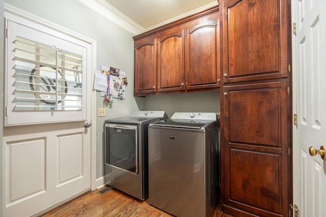 clothes washing area with crown molding, light hardwood / wood-style floors, cabinets, and washing machine and clothes dryer