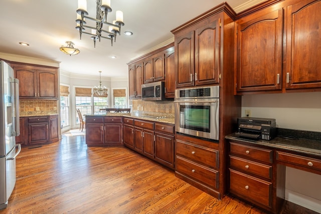 kitchen featuring wood-type flooring, decorative light fixtures, a chandelier, ornamental molding, and stainless steel appliances