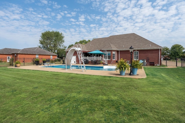 view of swimming pool with a patio, a water slide, and a yard