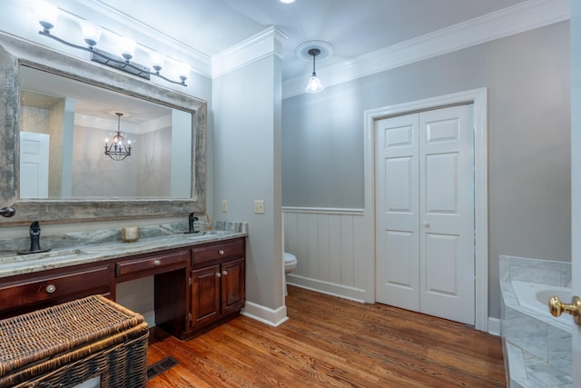 bathroom featuring hardwood / wood-style floors, vanity, ornamental molding, toilet, and tiled tub