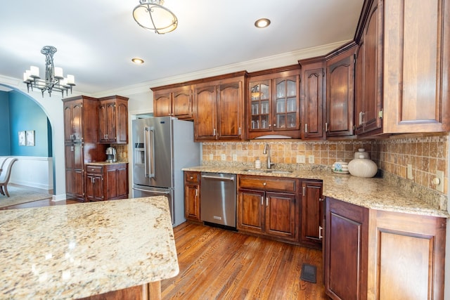 kitchen with sink, tasteful backsplash, hanging light fixtures, stainless steel appliances, and light hardwood / wood-style floors