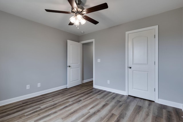 unfurnished bedroom featuring ceiling fan, baseboards, and wood finished floors