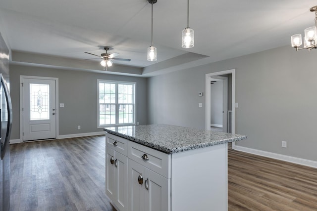 kitchen featuring baseboards, wood finished floors, a center island, and white cabinets