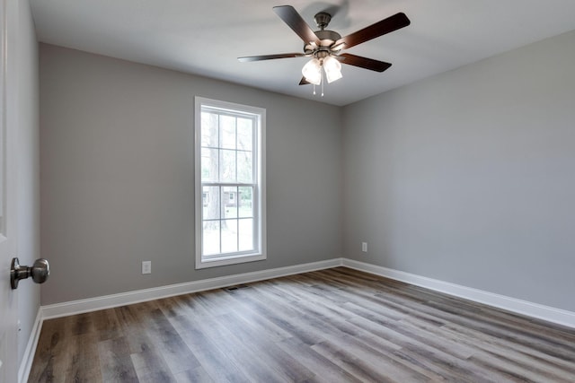 empty room featuring a ceiling fan, wood finished floors, visible vents, and baseboards