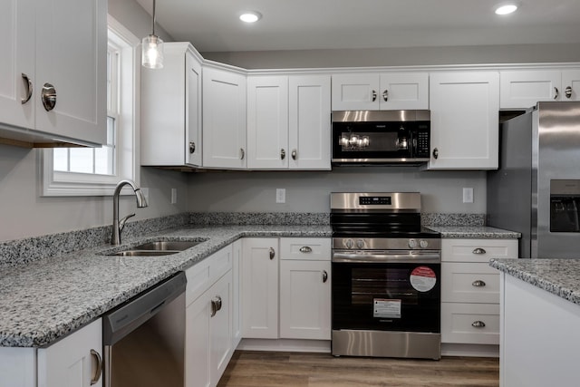 kitchen featuring recessed lighting, appliances with stainless steel finishes, white cabinetry, a sink, and wood finished floors