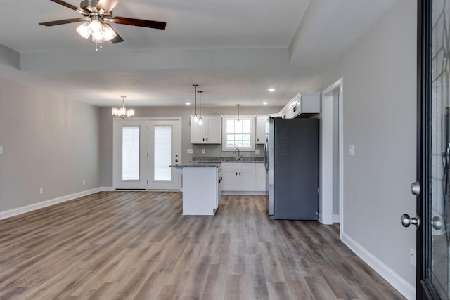 kitchen featuring baseboards, white cabinets, open floor plan, wood finished floors, and freestanding refrigerator